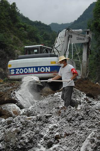 7月23日,在造成29人失踪的安康市平台汉滨区七堰村滑坡现场,一位抢险人员在洒消毒粉。新华社记者 丁海涛 摄